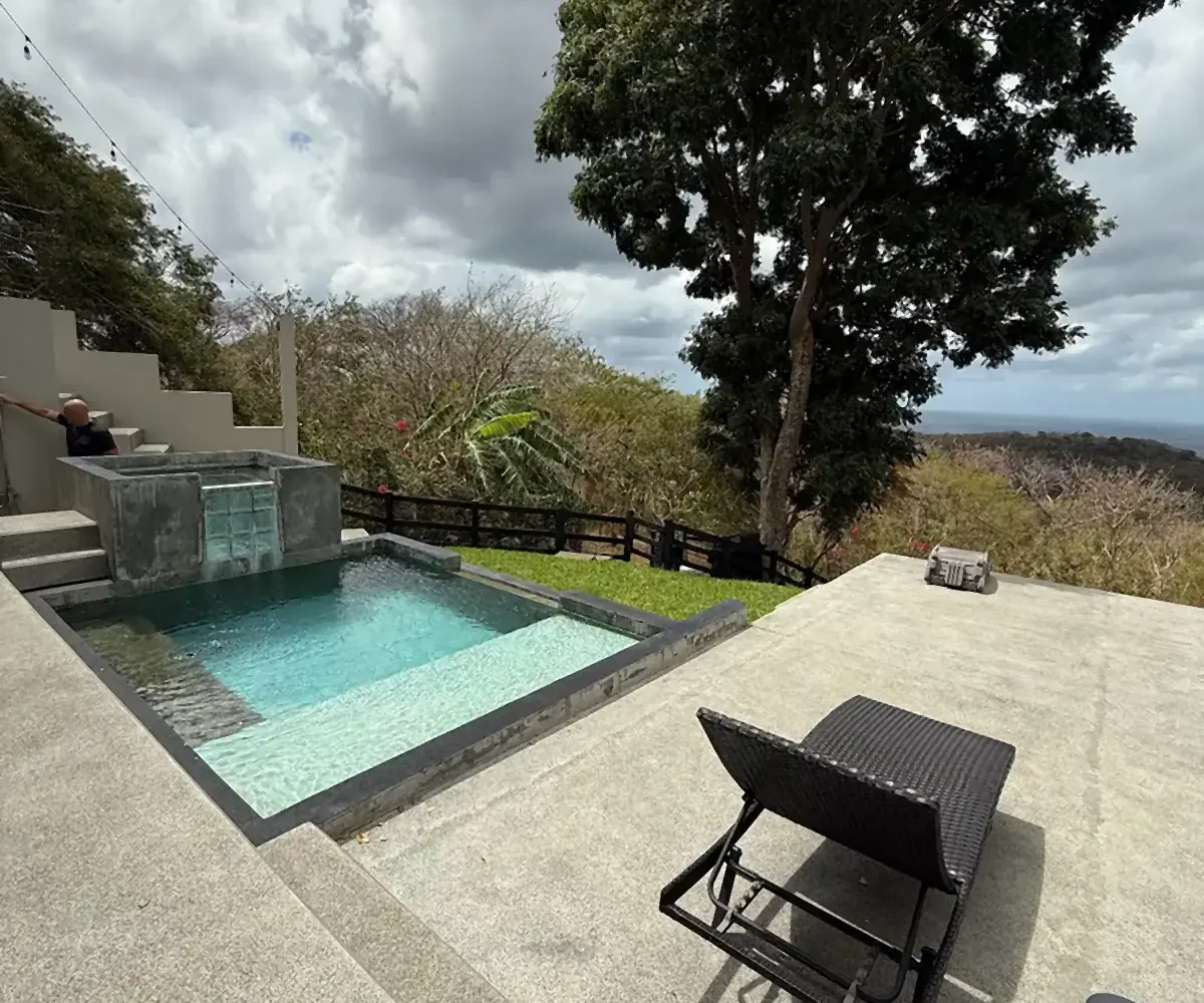 Piscina y césped con vista lejana al océano en Casa Cerca del Cielo, Rancho Santana