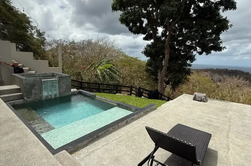 Piscina y césped con vista lejana al océano en Casa Cerca del Cielo, Rancho Santana
